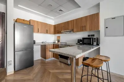 a kitchen with a stainless steel refrigerator and wooden cabinets at GuestReady Holiday Homes - Urban Elegance in JLT in Dubai