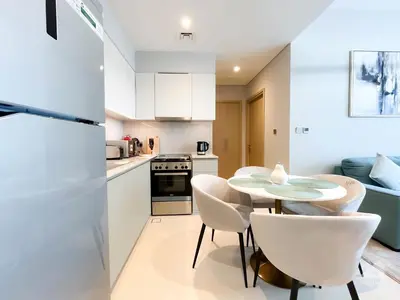 a kitchen with a small table and white chairs at Burj Royale Luxury 1B Balcony & City View Downtown in Dubai