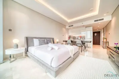 a bedroom with a large white bed and a dining room at Plush Studio at The Sterling East House Business Bay by Deluxe Holiday Homes in Dubai