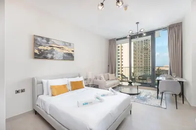 a white bedroom with a large bed and a living room at Dive into Luxury at LIV Residence - Suiteable in Dubai