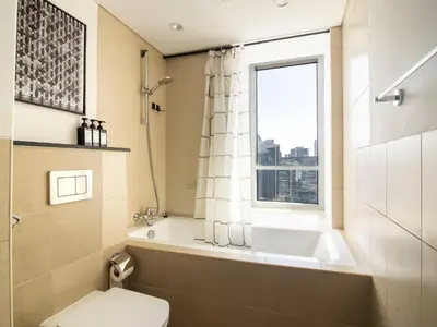 a bathroom with a tub and a toilet and a window at Downtown Chic Easy walk to Dubai Mall & Fountain in Dubai