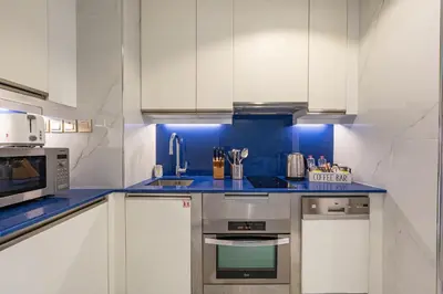 a kitchen with white cabinets and blue counter tops at Luxury Studio with Stunning Marina & Beach Views in Dubai