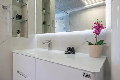 a white bathroom with a sink and a vase with a flower at Luxury Studio with Stunning Marina & Beach Views in Dubai