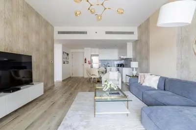 a living room with a blue couch and a table at Nasma Luxury Stays - Fabulous Apartment With Balcony Near MJL's Souk in Dubai
