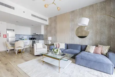 a living room with a blue couch and a table at Nasma Luxury Stays - Fabulous Apartment With Balcony Near MJL's Souk in Dubai