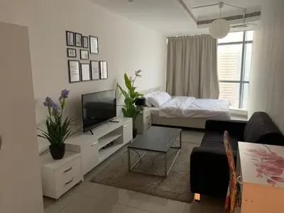 a white living room with a bed and a television at Coliving Sharing Hostel ll in Dubai