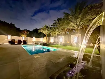 a swimming pool with a fountain in a backyard at night at Royal private pool, Lux 7-bedroom villa on Marina in Dubai