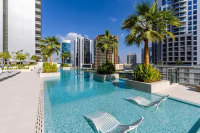 a swimming pool with two chairs and palm trees on a building at Maison Privee - Exquisite Duplex with Private Patio & Loft Living in Dubai