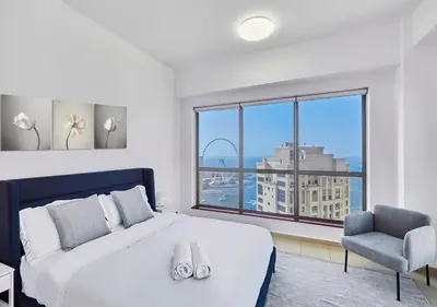 a bedroom with a bed and a chair and a large window at First Class Apartments in Heart of JBR, Steps to the Beach - 121 Living in Dubai