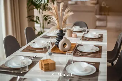 a dining room table with white dishes and a plant in a vase at Manzil - Luxury 4BR Penthouse with Harbour View & Private Terrace at Dubai Creek Harbour in Dubai