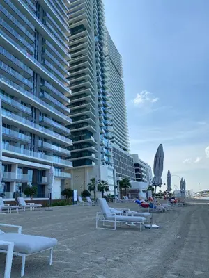 a beach with lounge chairs and a tall building at YOUR STAY APARTMENTS Luxury Beachfront Living in Dubai