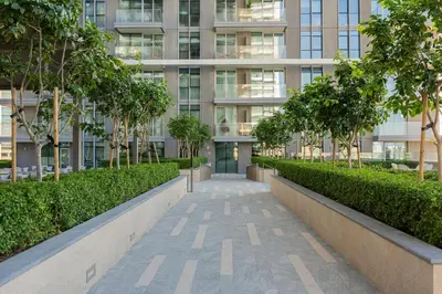 a walkway in front of a building with trees at YOUR STAY APARTMENTS Luxury Beachfront Living in Dubai