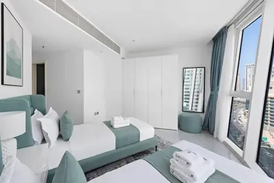 a white bedroom with a bed and a blue couch at StoneTree - Panoramic View - Spacious 2BR in Dubai
