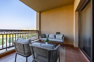 a balcony with a couch and a table and chairs at Apartment in Fairmont South Residence Palm Jumeirah in Dubai