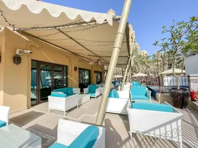 a group of chairs and tables on a patio at Apartment in Fairmont South Residence Palm Jumeirah in Dubai