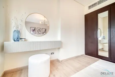 a white bathroom with a mirror and a stool at Gleeful 2BR at Sky Gardens DIFC by Deluxe Holiday Homes in Dubai