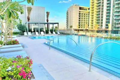 a large swimming pool with chairs and buildings at Luxury Dubai Creek Balcony & View in Dubai