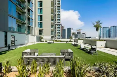 a patio with chairs and a lawn with buildings at Sleek One Bed Sobha Creek Vistas Reserve Tower A in Dubai