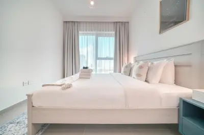 a bedroom with a large white bed with a window at Dubai Elegance: 1BR with DIFC & Zabeel Views in Dubai