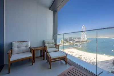 a balcony with two chairs and a view of the ocean at Manzil - 2BR Apartment in The Address JBR with Private Beach Access & Dubai Eye View in Dubai