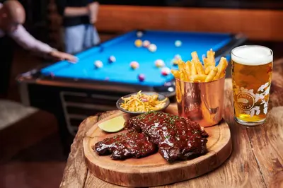 a wooden table with a plate of food and a drink at FIVE LUXE in Dubai