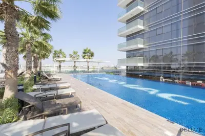 an exterior view of a building with a swimming pool at Appealing Studio at Carson C DAMAC Hills Dubailand by Deluxe Holiday Homes in Dubai