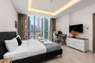 a bedroom with a bed and a desk and a television at Luxury 1BR Apartment with Burj Khalifa View at Sterling in Dubai