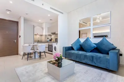 a living room with a blue couch and a kitchen at STAY BY LATINEM Luxury 1BR Holiday Home CVR B1701 near Burj Khalifa in Dubai