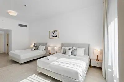 a white bedroom with two beds and two lamps at Luxury 4BR Townhouse Palm Jumeirah in Dubai