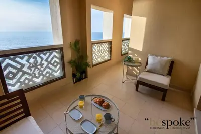 a living room with a table and a balcony with the ocean at Bespoke Holiday Homes - Palm Jumeirah -2 Bedroom Sea View with Beach Access, Balqis in Dubai