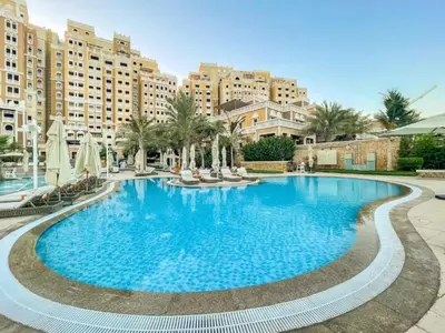 a large swimming pool in a resort with buildings at Bespoke Holiday Homes - Palm Jumeirah -2 Bedroom Sea View with Beach Access, Balqis in Dubai