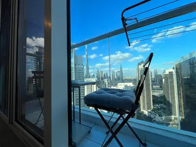 a chair on a balcony with a view of the city at Damac Maison Prive DVR Vacation Homes in Dubai
