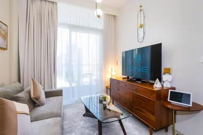 a living room with a couch and a television on a dresser at Burj View Apartment at Vera, Business Bay in Dubai