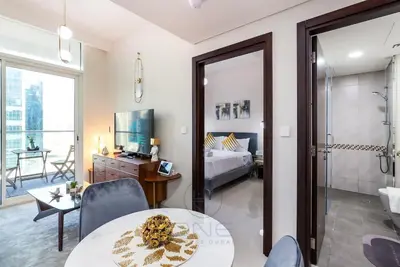 a living room with a table and a bedroom at Burj View Apartment at Vera, Business Bay in Dubai