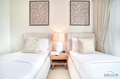 two beds in a room with a nightstand between them at Stylish 2BR with Burj Khalifa View at Burj Royale Downtown Dubai by Deluxe Holiday Homes in Dubai