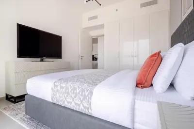 a white bedroom with a large bed with a flat screen tv at Frank Porter - Downtown Views II in Dubai