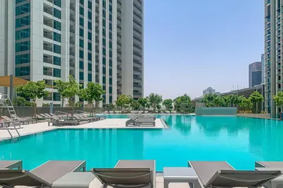 a large swimming pool with chairs and blue water at Frank Porter - Downtown Views II in Dubai