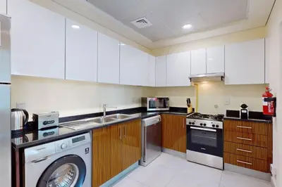 a kitchen with white cabinets and a washing machine at Marina Arcade - Neat Two Bedroom in Dubai