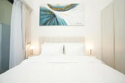 a bedroom with a white bed with a painting on the wall at Cozy Flat in Business Bay in Dubai