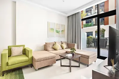 a living room with a couch and two chairs and a tv at StoneTree - Furnished 1BR minutes of drive away to Expo 2020 in Dubai