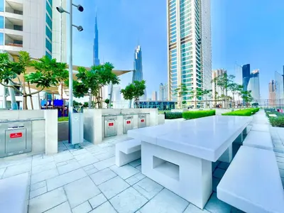a white table and benches on a patio with buildings at Downtown Views 1BR - Dubai Mall, Fountain & Burj Khalifa access in Dubai