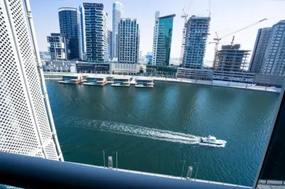 a boat in a river in a city with buildings at Elegant 1bedroom in J ONE in Dubai