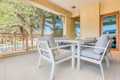 a dining room with a table and chairs and a balcony at Direct Access to Nakheel Mall At the Heart of The Palm in Dubai