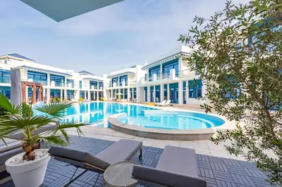 a large swimming pool in front of a building at Stunning Palm Villa with Rooftop Garden, Resort Style Pool and Beach by Exclusive Holiday Homes in Dubai