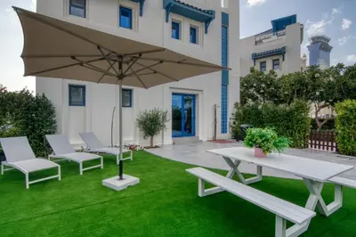 a patio with a table and chairs and an umbrella at Stunning Palm Villa with Rooftop Garden, Resort Style Pool and Beach by Exclusive Holiday Homes in Dubai
