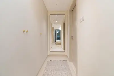 a hallway with white walls and a mirror at Burj Khalifa Views / 5 min walk from Dubai Mall / Dubai Opera / Upgraded / Designer Choice / 8 people / The Best Location in Dubai