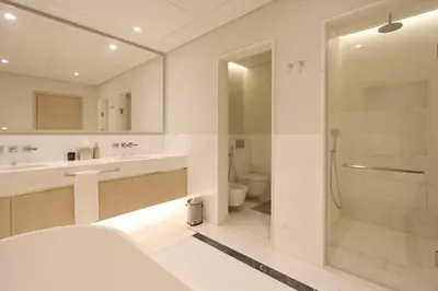 a white bathroom with a shower and a toilet at Livbnb Suites - 1BR w/ Sea View in Palm Tower in Dubai