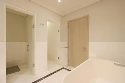 a white bathroom with a shower and a bed at Livbnb Suites - 1BR w/ Sea View in Palm Tower in Dubai