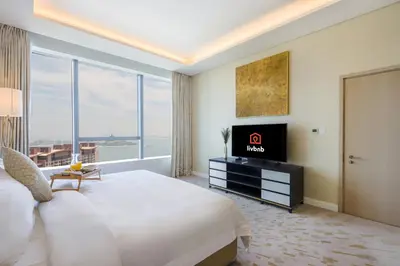 a hotel room with a large bed and a television at Livbnb Suites - 1BR w/ Sea View in Palm Tower in Dubai