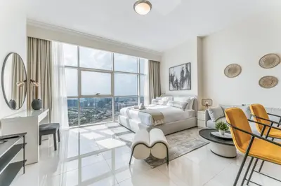 a white bedroom with a bed and a large window at Studio in Reef Residence JVC by PK Holidays in Dubai